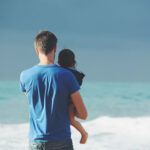 Dad holding child while looking out at water