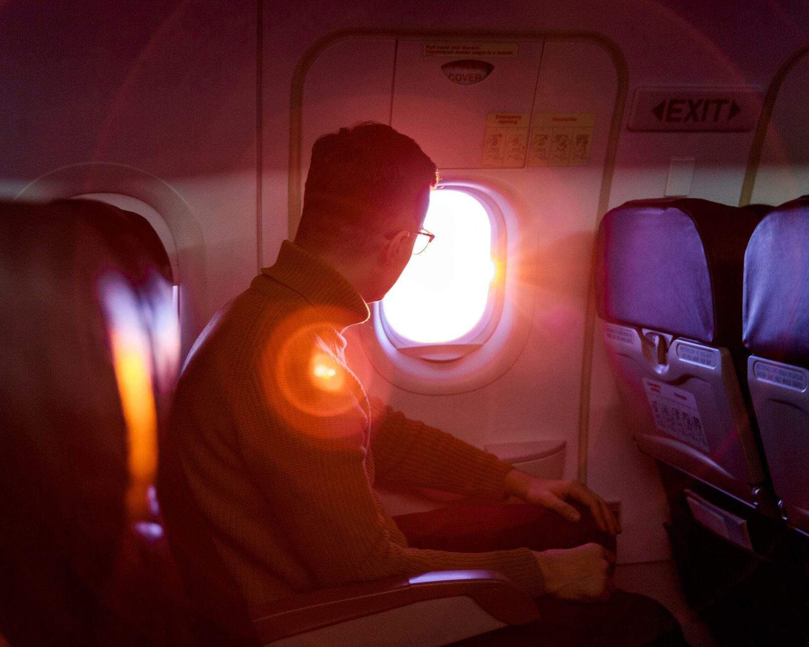 Man watching sunset from airplane window.