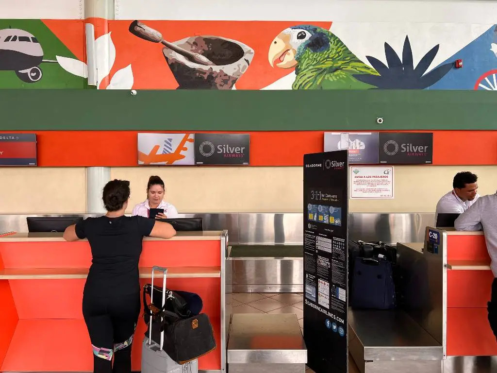 Woman stands at Silver Airways check-in counter.