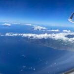 How long is a flight to Hawaii? View over Hawaii. Photo taken from the airplane with the wing in the forefront and the island below.