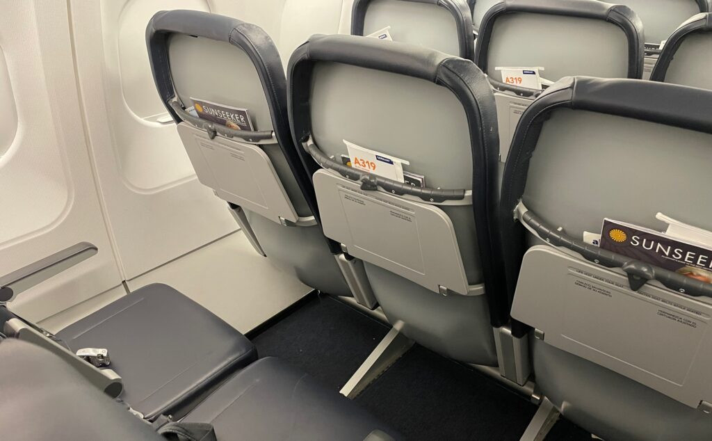 Allegiant A319 cabin showing blue seat covers on slim seats and gray seatbacks, highlighting the basic interior.