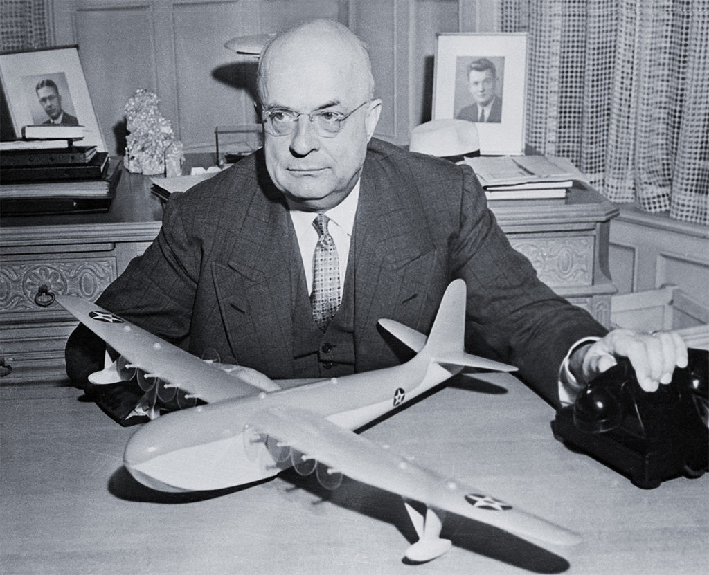 Henry J. Kaiser, shipbuilder, with a model of the H-4 Hercules, highlighting the ambitious scale of the project.