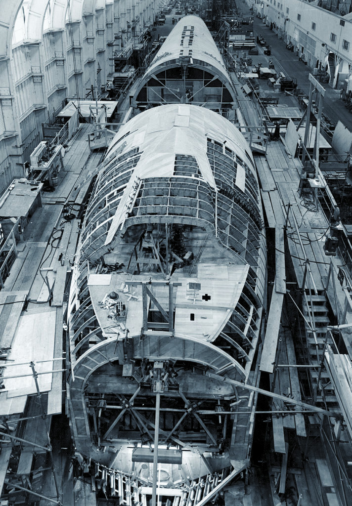 The H-4 Hercules under construction, dwarfing the workers and highlighting the immense scale of the aircraft.