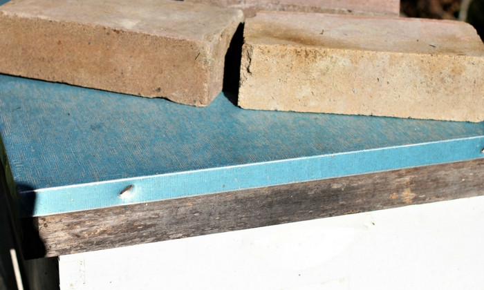 Beehive secured with bricks on top to prevent lid from blowing off during a storm.