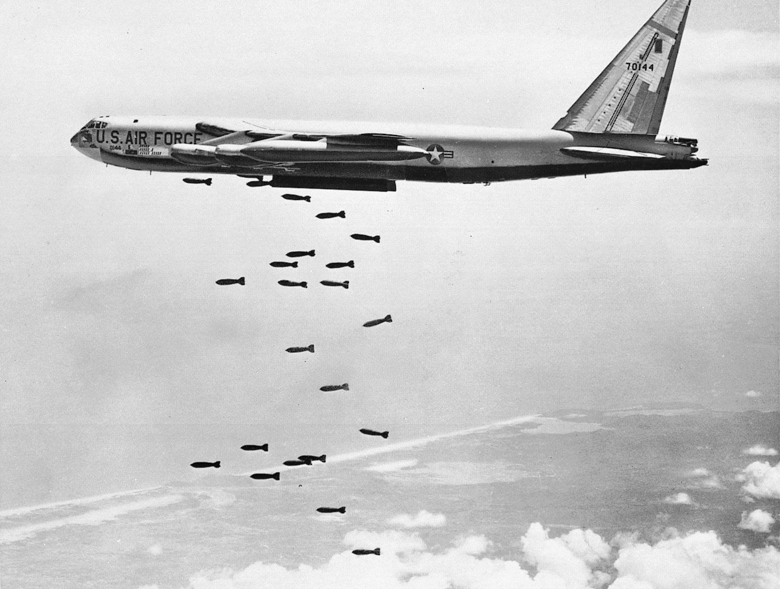 Boeing B-52 Stratofortress bombing Vietnam, alt text: A Boeing B-52 Stratofortress bomber releases a stream of bombs over Vietnam during the Vietnam War, showcasing its bombing capabilities.