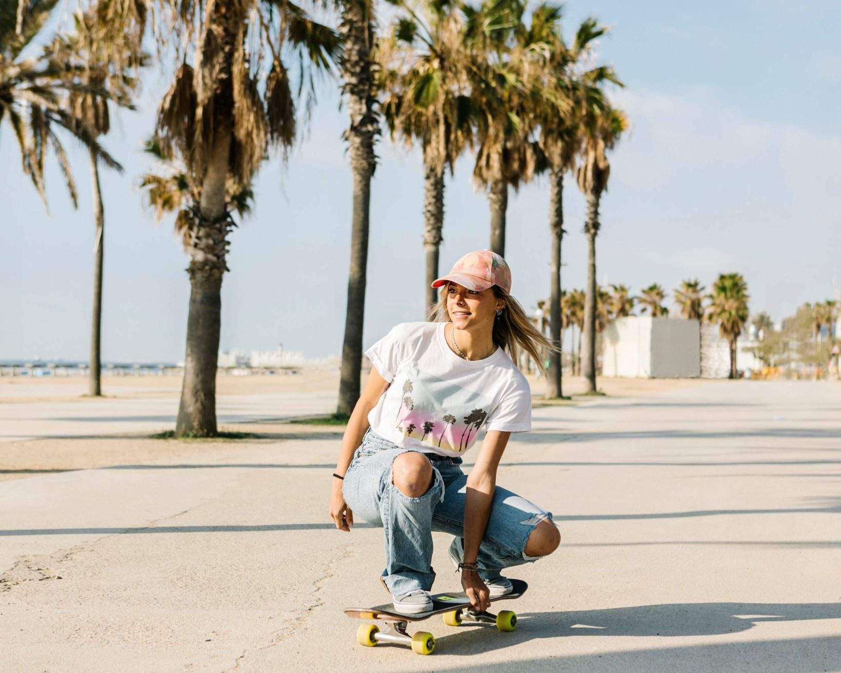 A skateboarder riding on the beach promenade in Miami, with palm trees lining the path.