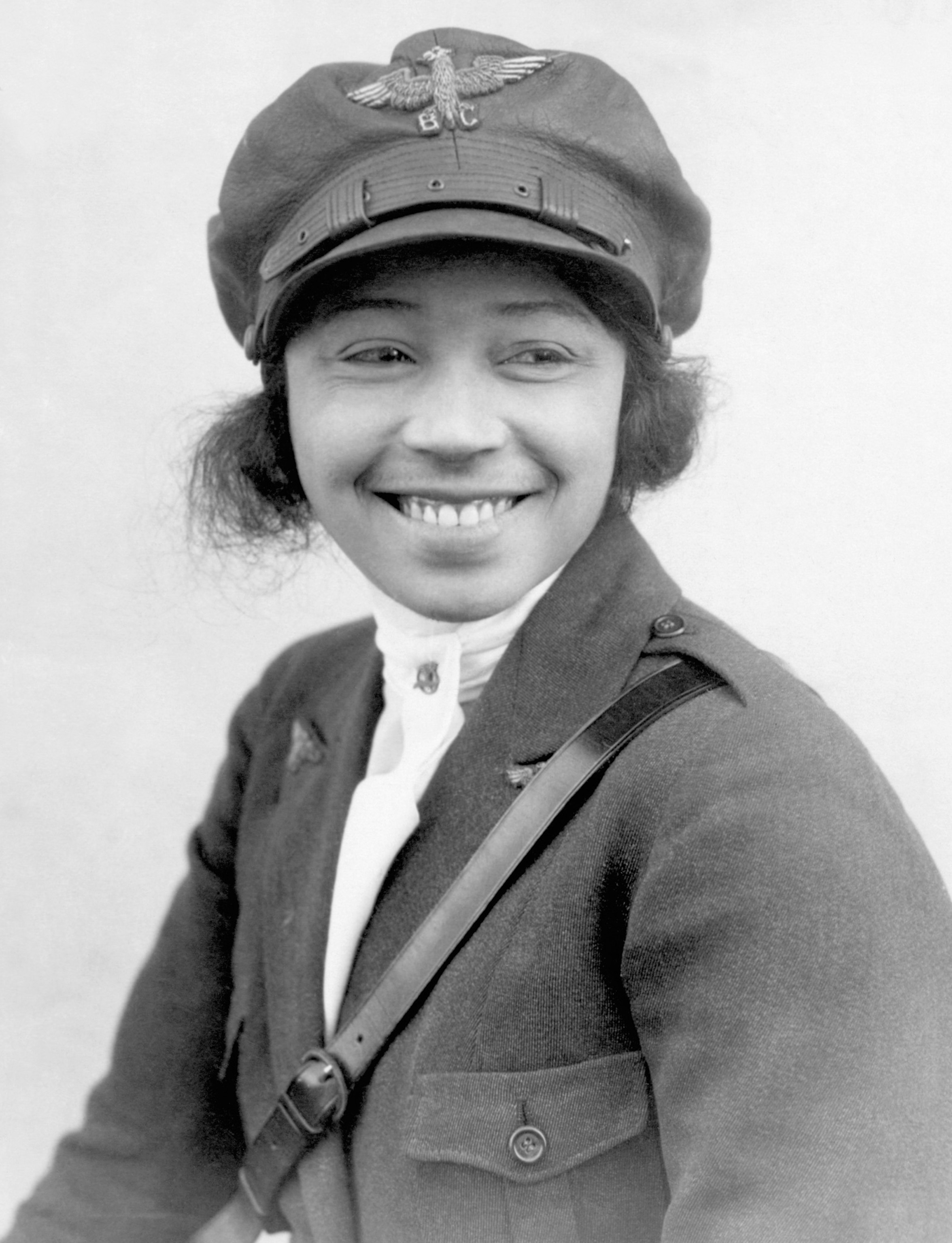 Black and white portrait of pilot smiling with hat on.