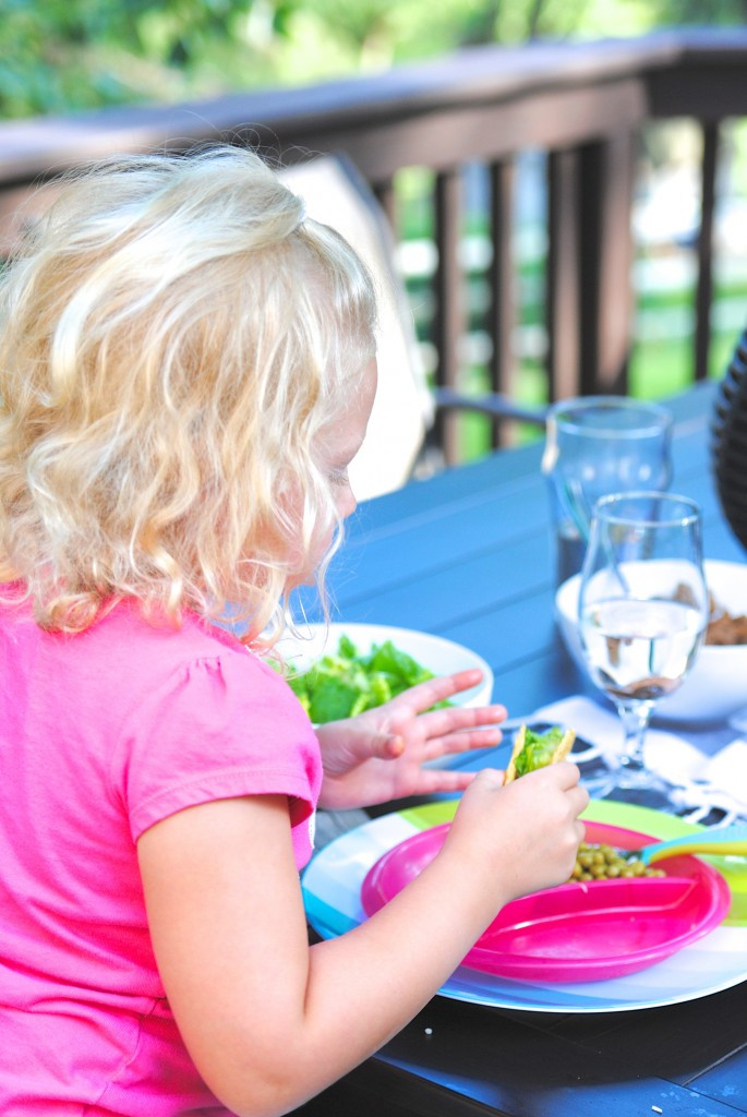 A child enjoying a meal at a picnic table, undisturbed by flies thanks to the penny trick