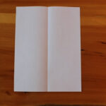 Paper folded in half lengthwise to create center crease.