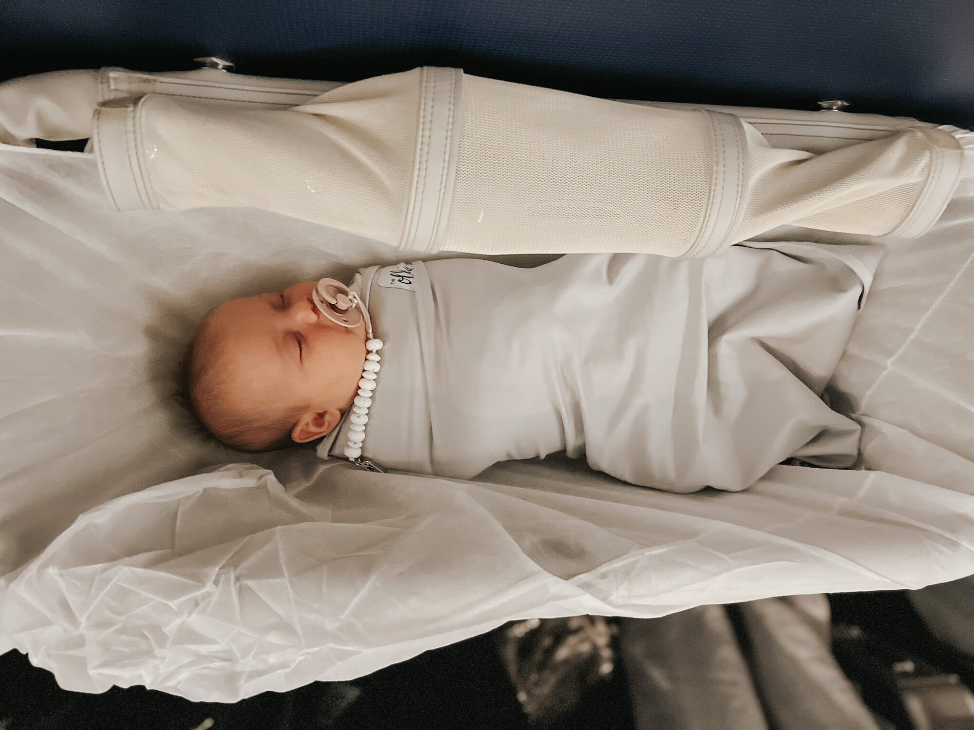 Infant sleeping in an airplane bassinet during international flight