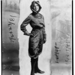 Woman stands for portrait with pilots gear on.