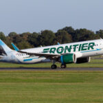 Frontier Airlines Airbus A320 landing at an airport, showcasing the airline's branding with an animal on the tail fin.