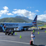 Passengers waiting at airport gate, alt text: Passengers await standby confirmation at the airport gate for an American Airlines flight