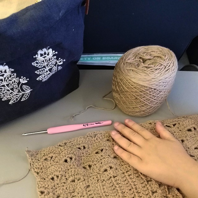 Woman crocheting on a plane, happy and relaxed