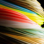 Louis Cahill's vibrant fly fishing image showcasing various colored fly lines and emphasizing the debate on whether color spooks fish.