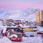 Aerial view of Nuuk, Greenland, showcasing the city's coastal location and colorful buildings against a backdrop of fjords and mountains