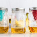 Three mason jars, each with a fruit fly funnel. One red, one white and one teal