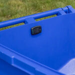 Garbage guard attached to the lid of a blue trash can