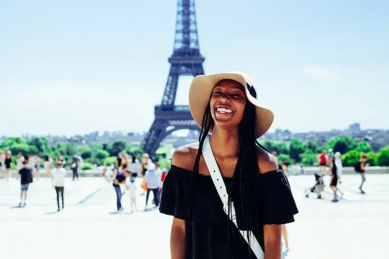 Smiling traveler with the Eiffel Tower in the background, representing successful international travel
