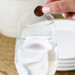 Dropping a penny in a full glass of water to keep flies away