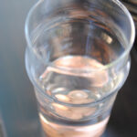 A full glass of water with pennies at the bottom