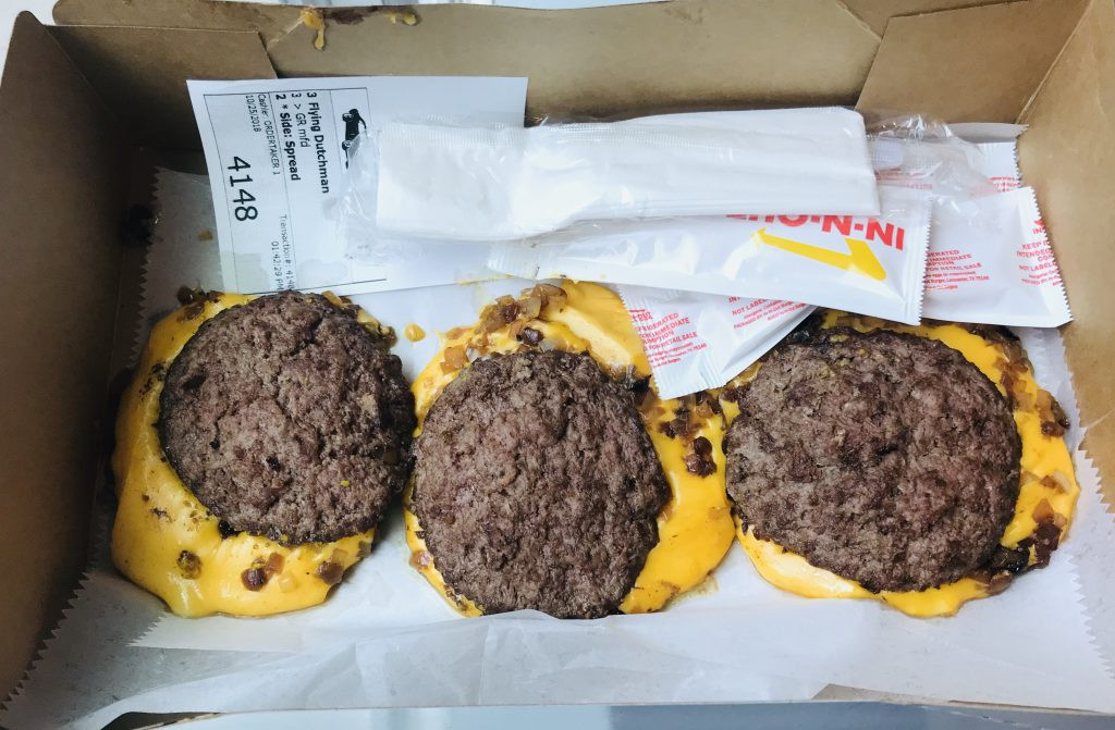 In-N-Out Flying Dutchman featuring two beef patties and melted cheese, displayed in a well-lit setting to highlight its simplicity and appeal to keto dieters