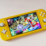 A yellow Nintendo Switch Lite with the Mario Kart 8 Deluxe homescreen on it