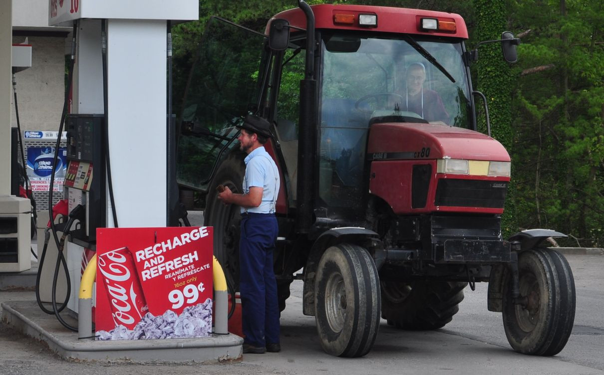 Amish person filling up the tractor.