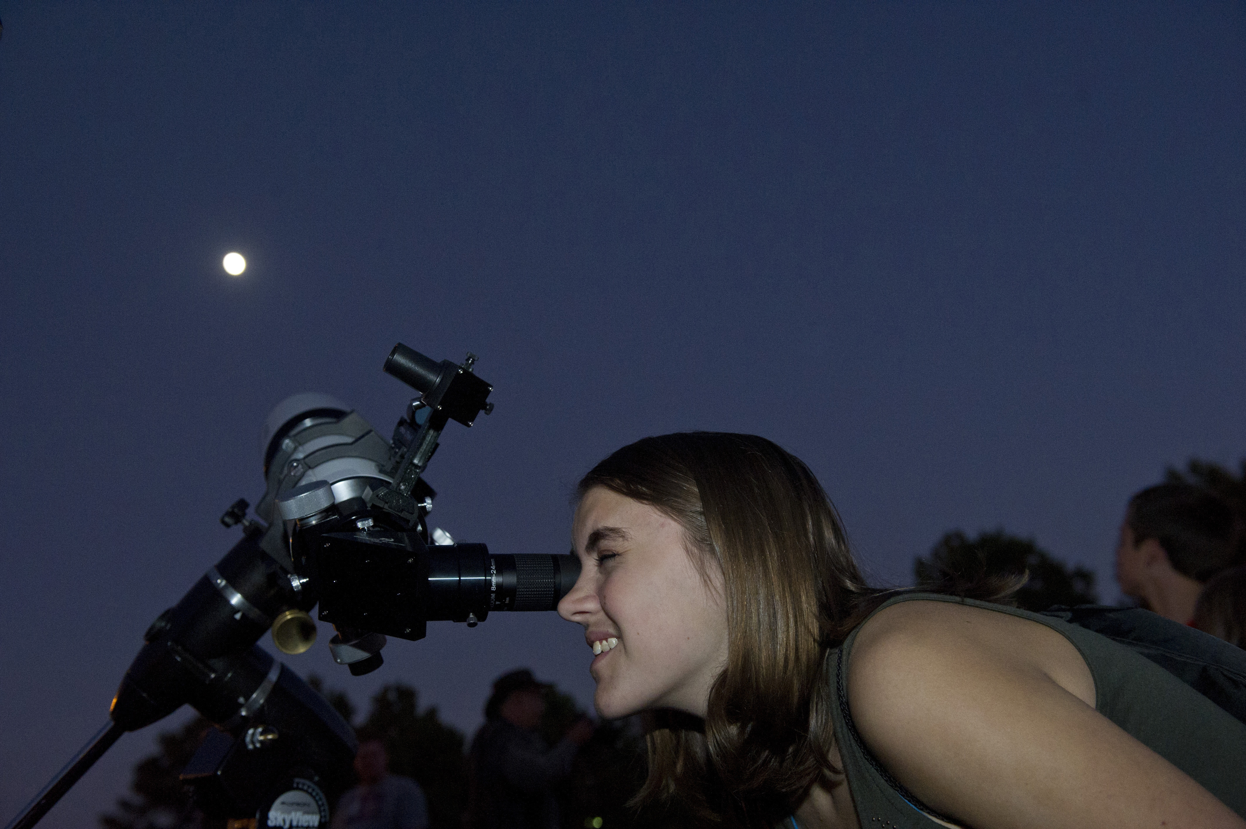 A person looking through a telescope pointed at the sky at night.