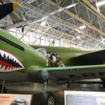 Flying Tigers pilots posing in front of a P-40 Warhawk showcasing the iconic shark teeth design, a symbol of their daring and innovative tactics