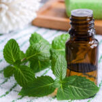 Peppermint sprig next to an amber glass bottle