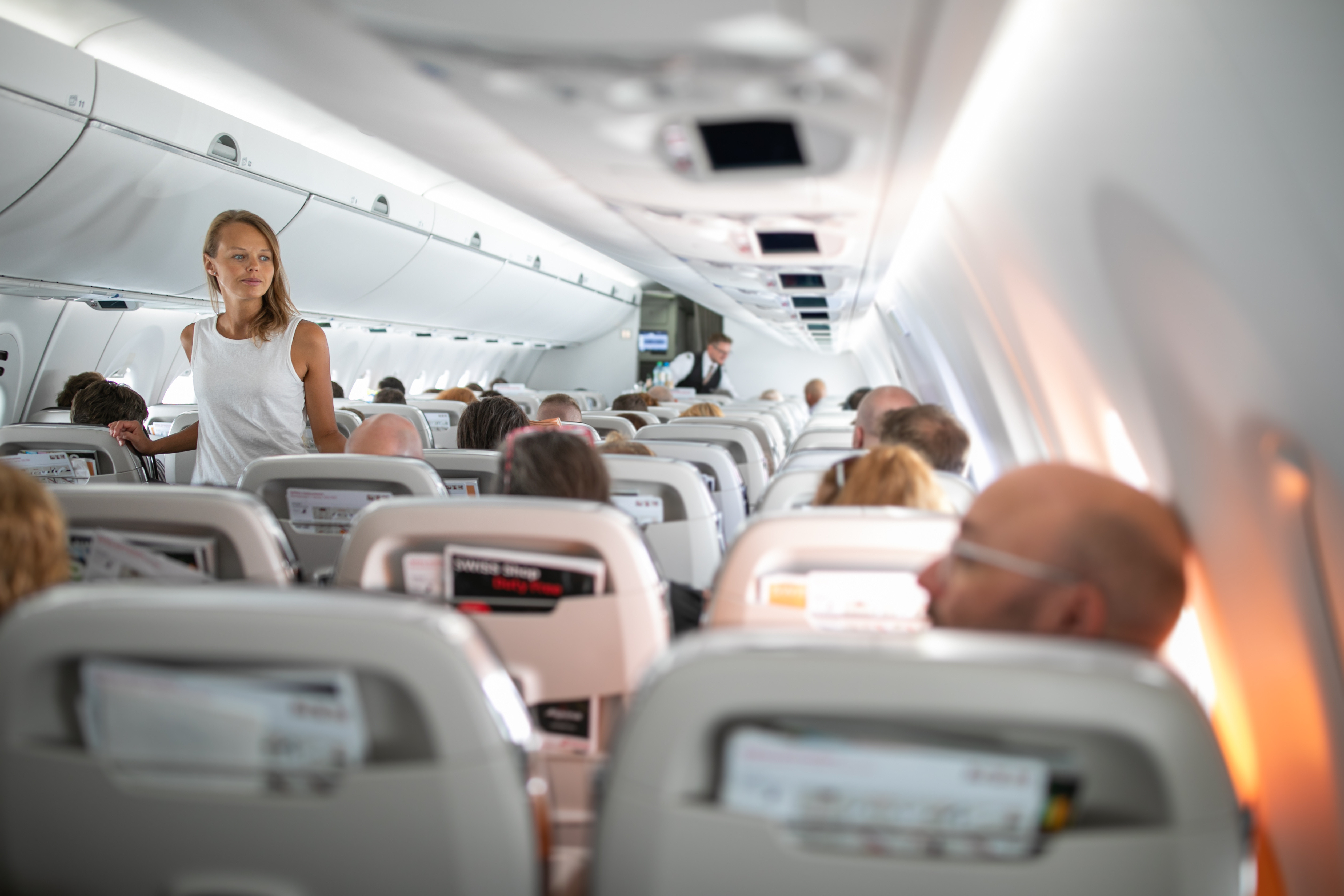 Young woman stretching her legs and walking in the airplane aisle during a long haul flight.