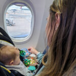 Baby in car seat looking out plane