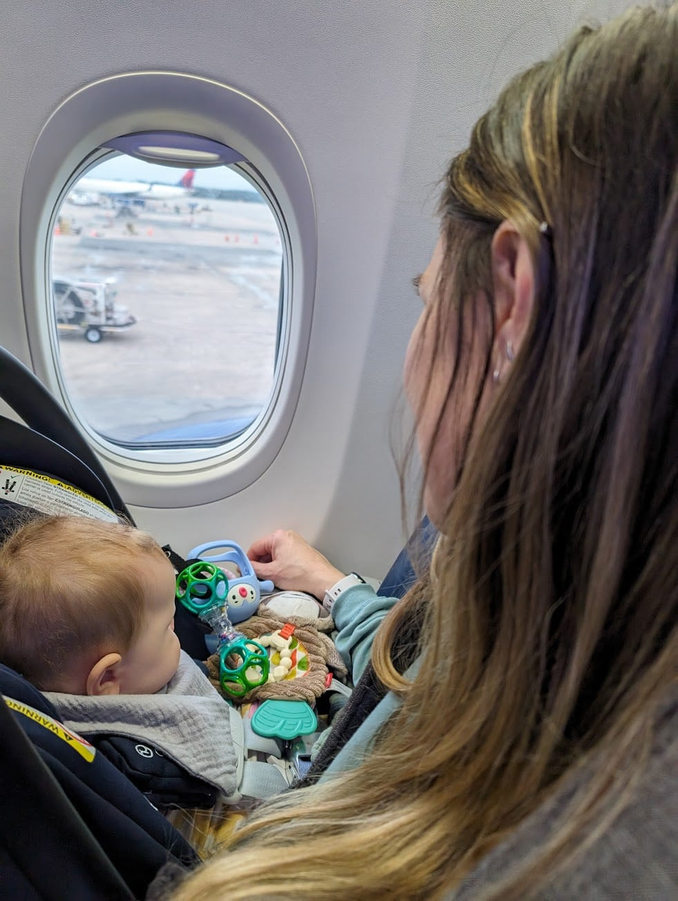 Baby in car seat looking out plane