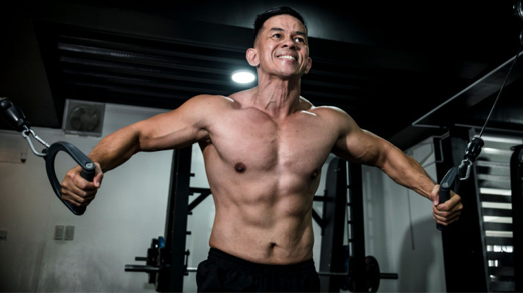 A muscular person in a gym performing a cable chest exercise