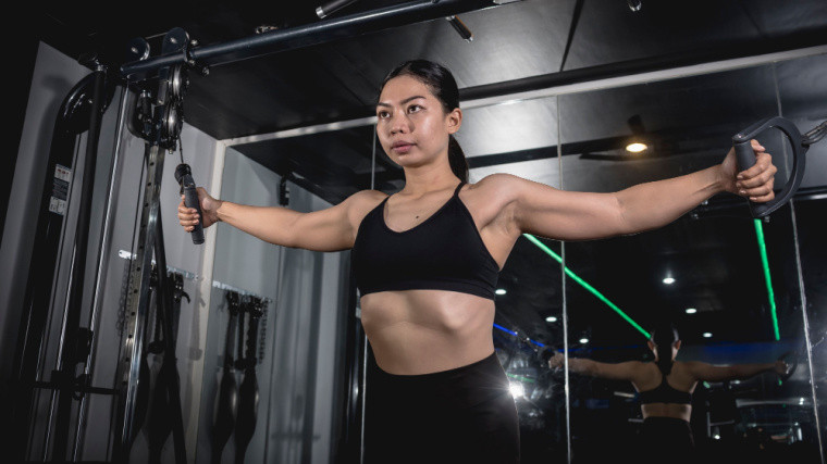Person standing in a gym setting up for a cable chest flye