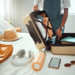 Woman packing a suitcase with sunscreen and other travel essentials
