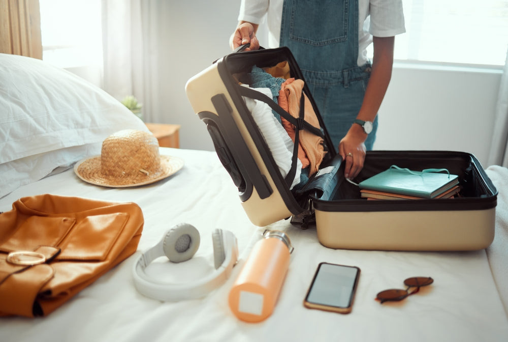 Woman packing a suitcase with sunscreen and other travel essentials