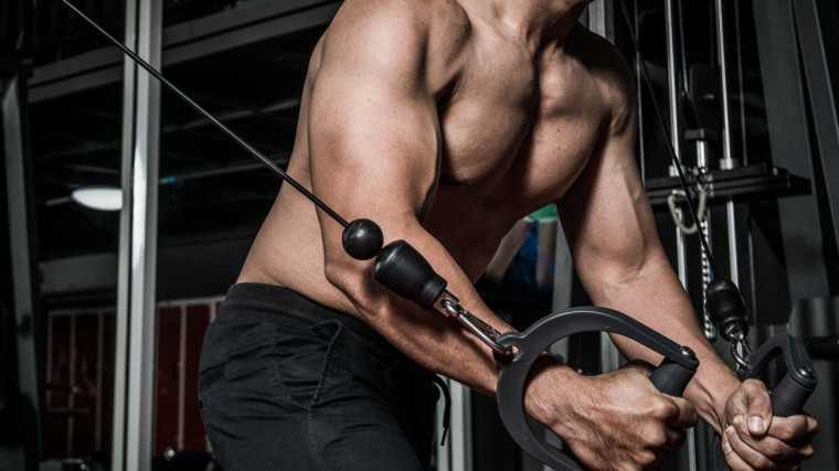 A muscular person using a cable chest machine