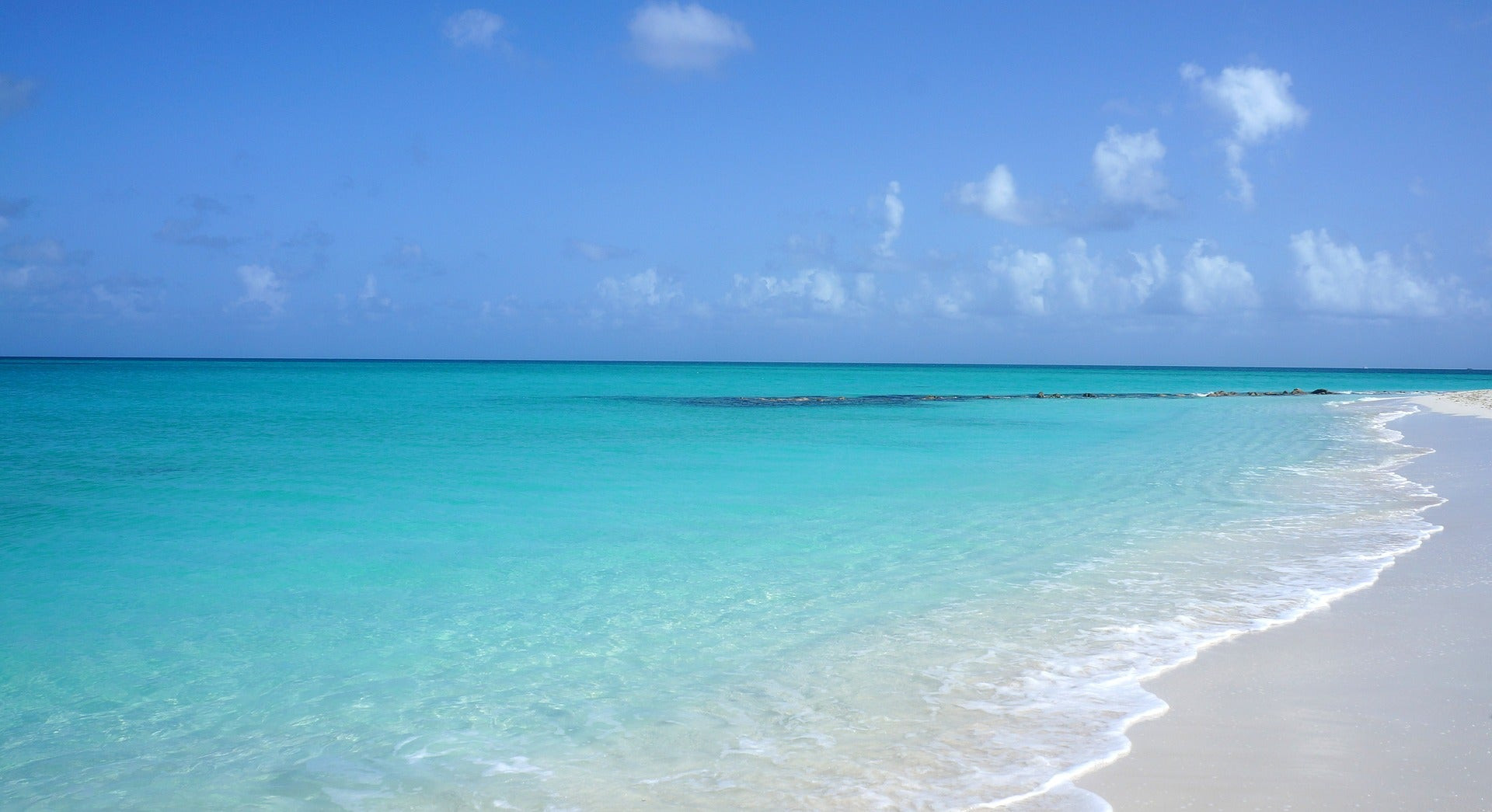 Aerial view of a Southwest Airlines aircraft landing at a Caribbean airport, showcasing the turquoise waters and white sandy beaches