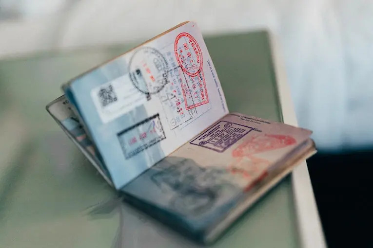 Passport opened to a page filled with entry and exit stamps from various countries, representing international travel