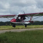 Ultralight aircraft flying over a rural landscape
