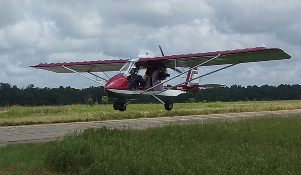 Ultralight aircraft flying over a rural landscape