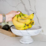 Removing bananas from a marble fruit stand to get rid of fruit flies