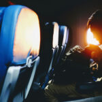 Man looking in his bag sitting on plane seat from Bambi Corro. The man is searching for the nicotine pouches to get rid of nicotine craving