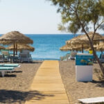 Beach with umbrellas and sunbeds in Santorini, Greece