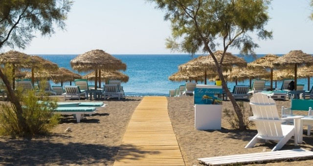 Beach with umbrellas and sunbeds in Santorini, Greece
