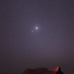 Venus and Jupiter in close conjunction over a silhouetted landscape
